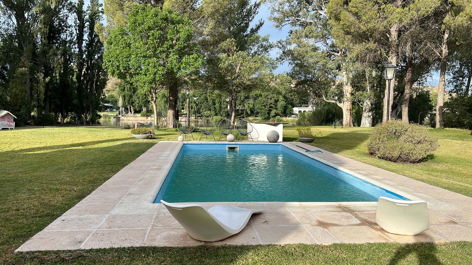 Pileta rodeada de parque con el río de fondo